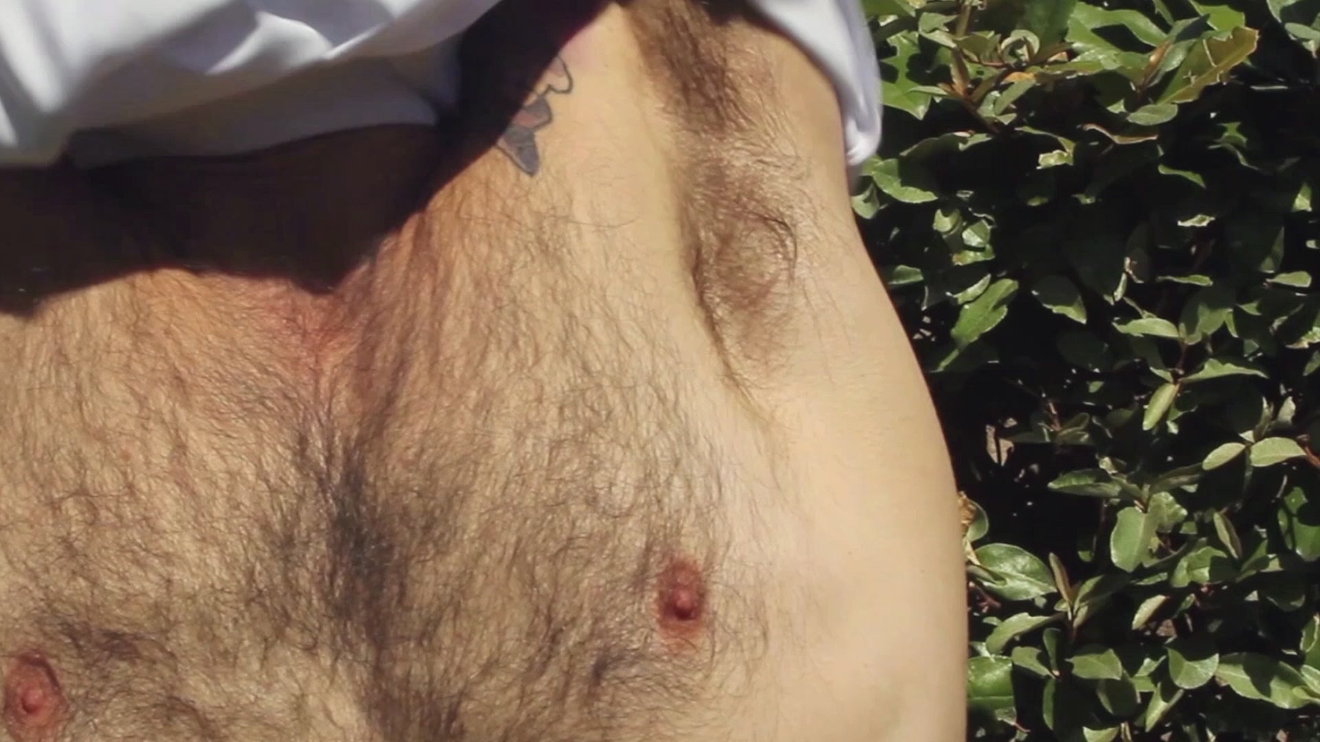 Charger la vidéo : 8-second video of a model putting on and taking off a white Out Now! t-shirt featuring a peach pattern, showcasing the playful LGBTQ+ design in action.